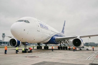 Avion de ligne commercial Boeing ou Airbus sur le tarmac d'un aéroport international, entouré de techniciens en gilets orange effectuant des vérifications pré-vol